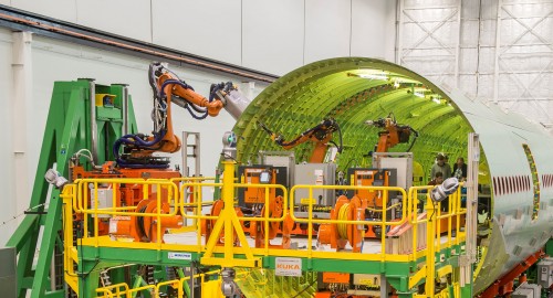 Photo and press release from Boeing: EVERETT, Wash., July 14, 2014 /PRNewswire/ -- Boeing [NYSE: BA] today announced that it is in the final phases of testing and production readiness of a new method for building 777 fuselages as part of its ongoing technology investment strategy. Known as the Fuselage Automated Upright Build, or FAUB, this Advanced Manufacturing technology improves workplace safety and increases product quality. This technology has been in development by Boeing since 2012. With this new technology, fuselage sections will be built using automated, guided robots that will fasten the panels of the fuselage together, drilling and filling the more than approximately 60,000 fasteners that are today installed by hand. FAUB offers numerous benefits including an improvement in employee safety. The nature of the drilling and filling work makes it ideal for an automated solution. More than half of all injuries on the 777 program have occurred during the phase of production that is being automated. In addition, the automated system is expected to reduce build times and improve first-time quality of the build process. "This is the first time such technology will be used by Boeing to manufacture widebody commercial airplanes and the 777 program is leading the way," said Elizabeth Lund, vice president and general manager, 777 program and Everett site, Boeing Commercial Airplanes. "We're excited to continue improving the production process here and we're positioning ourselves to begin building 777X airplanes in the future." The 777 program has already begun testing FAUB at a facility in Anacortes, Wash. Production readiness preparations are underway and the system will be installed in Everett in a new portion of the main factory that is under construction now. The technology is expected to be implemented in the next few years. The robotic system, designed for Boeing by KUKA Systems, is the latest in a series of strategic Advanced Manufacturing moves on the 777 program, which have already included new systems for painting wings and other drilling operations.