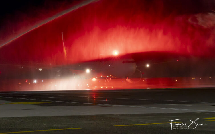 The 777's red strobes made some great lighting effects as the jet passed beneath the crossed streams of water